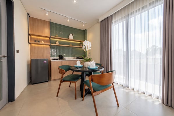 A modern kitchen with a dining area, featuring a refrigerator, cabinets, and a table with chairs. - TheNomad Canggu (Canggu)