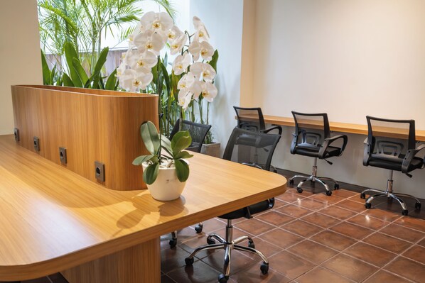 A conference room with a wooden table, potted plants, and office chairs. - TheNomad Canggu (Canggu)