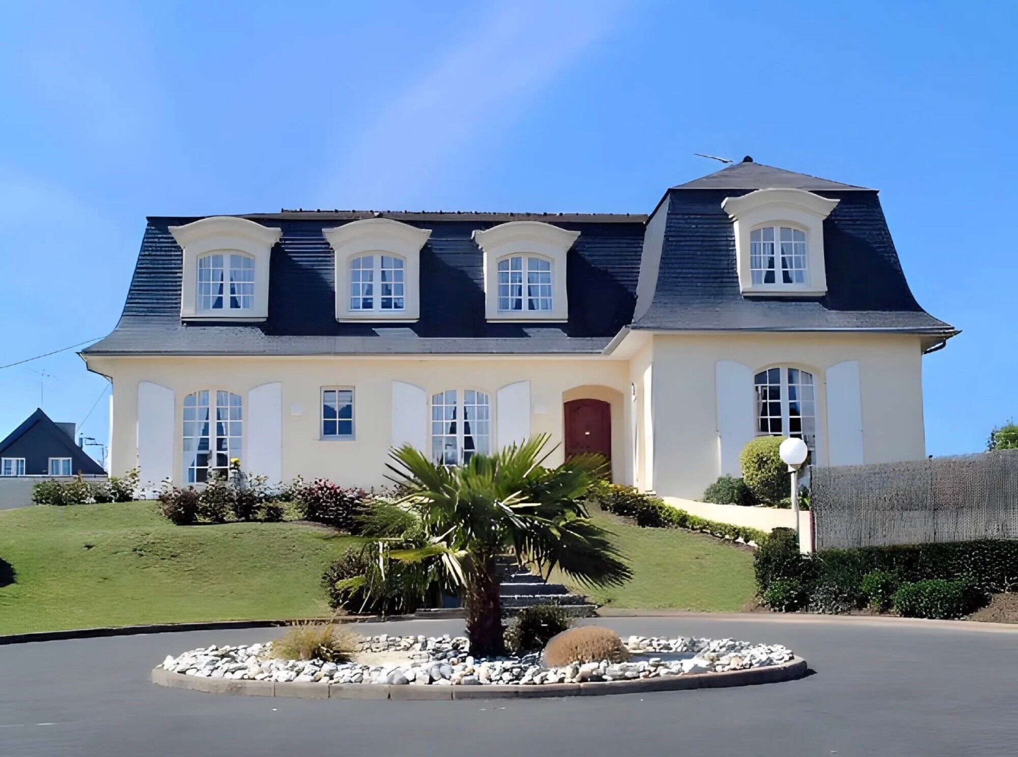 A large, two-story house with a symmetrical facade, multiple windows, and a central entrance.
