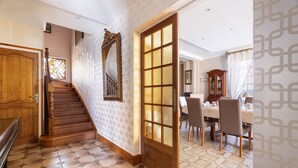 Una escalera conduce a un comedor con piso estampado, una puerta de madera y una mesa con sillas.