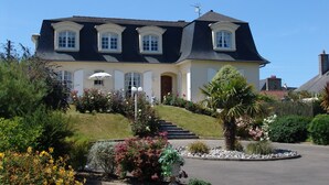 Ein zweistöckiges Haus mit dunklem Dach, weißen Außenwänden und einem Eingangsbereich mit Stufen.