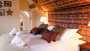 Una cama bien tendida con sábanas blancas y almohadas decorativas, un cabecero estampado y un adorno con forma de estrella en la pared.