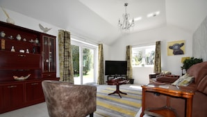 A living room with a brown armchair, a wooden side table, a television, and a sofa.
