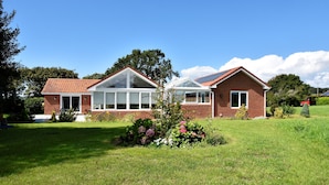 A two-story house with a brick exterior, a large glass window, and a solar panel on the roof.