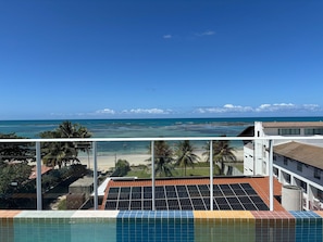 En pool med solpaneler, udsigt til en strand og en klar himmel.