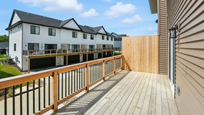 A residential building with a wooden deck and a garage. - Modern Townhome Retreat In Prime Location 3 Bedroom Townhouse (Iowa City)