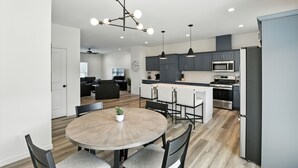 A modern kitchen with dark cabinets, a central island, and stainless steel appliances. - Modern Townhome Retreat In Prime Location 3 Bedroom Townhouse (Iowa City)