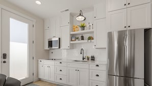 A modern kitchen with white cabinets, a stainless steel refrigerator, a microwave, and a sink. - Southwest Casita 1 Bedroom Home (St. George)