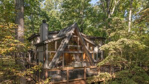 Une cabane dotée d’une terrasse en bois, de grandes fenêtres et d’une cheminée.