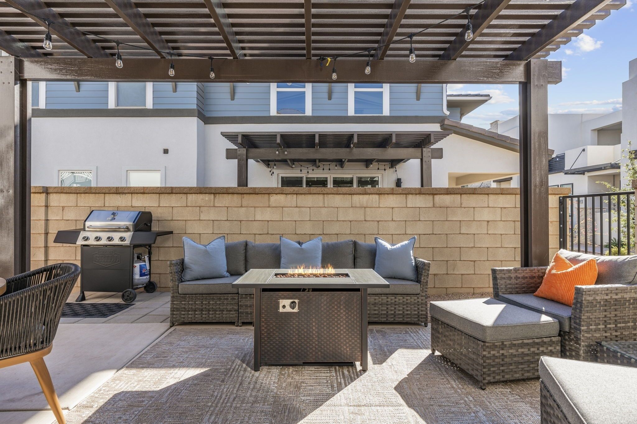 An outdoor patio with a grill, seating area, and a fire feature.