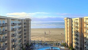 A beachfront hotel with multiple balconies, a swimming pool, and a beach view. - Cozy 1-bedroom condo in serene Seaside with fitness room, AC (Seaside)