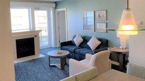 A living room with a fireplace, a sofa, a coffee table, and a lamp. - Cozy 1-bedroom condo in serene Seaside with fitness room, AC (Seaside)
