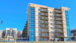 A multi-story hotel with a modern design, featuring balconies on each floor and large windows. - Cozy 1-bedroom condo in serene Seaside with fitness room, AC (Seaside)