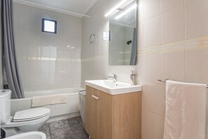 Et badeværelse med toilet, håndvask og badekar.