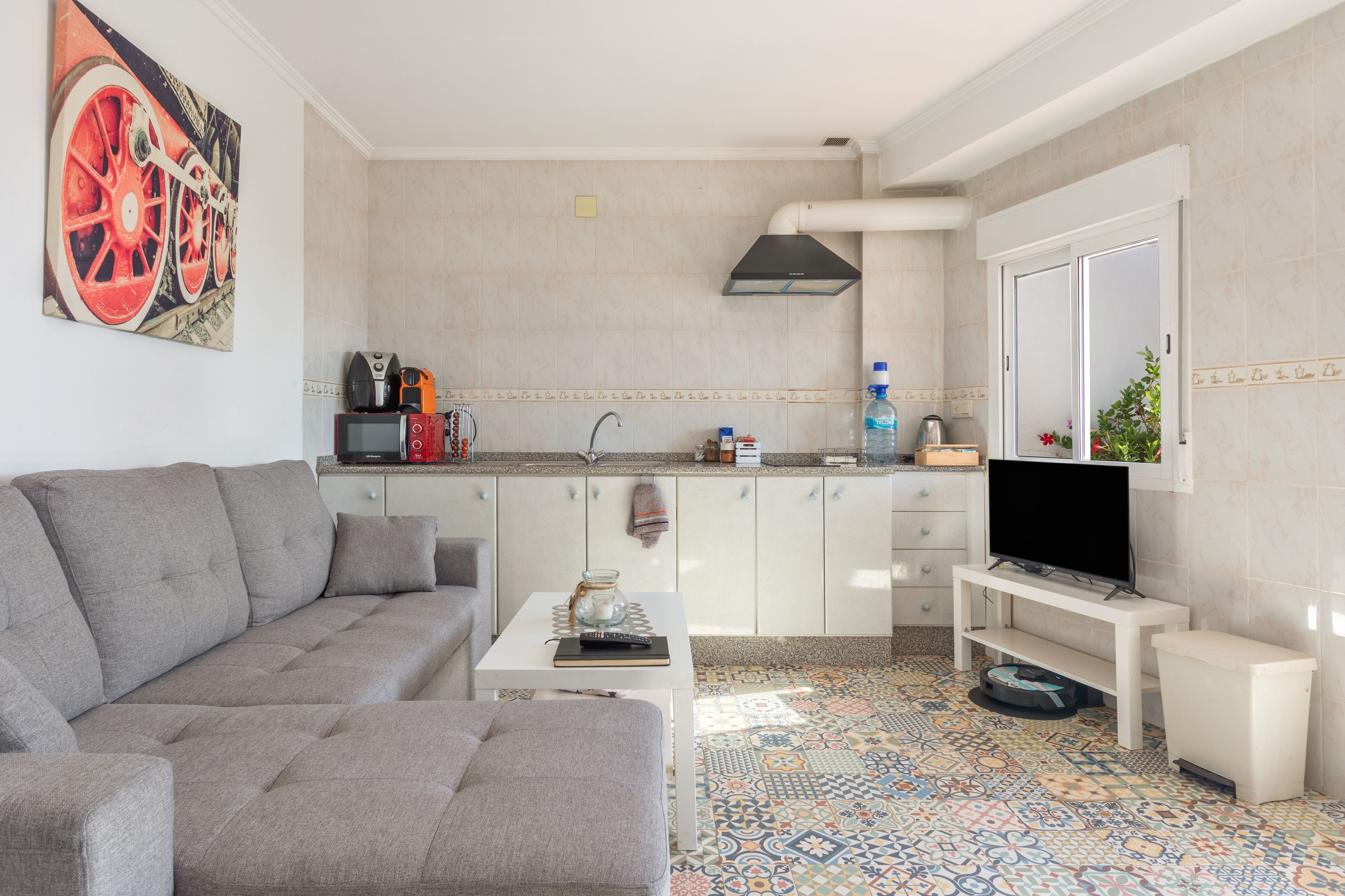 Una sala de estar moderna con un sofá gris, una mesa de centro y un televisor sobre un mueble.