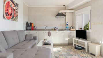 Una sala de estar moderna con un sofá gris, una mesa de centro y un televisor sobre un mueble.