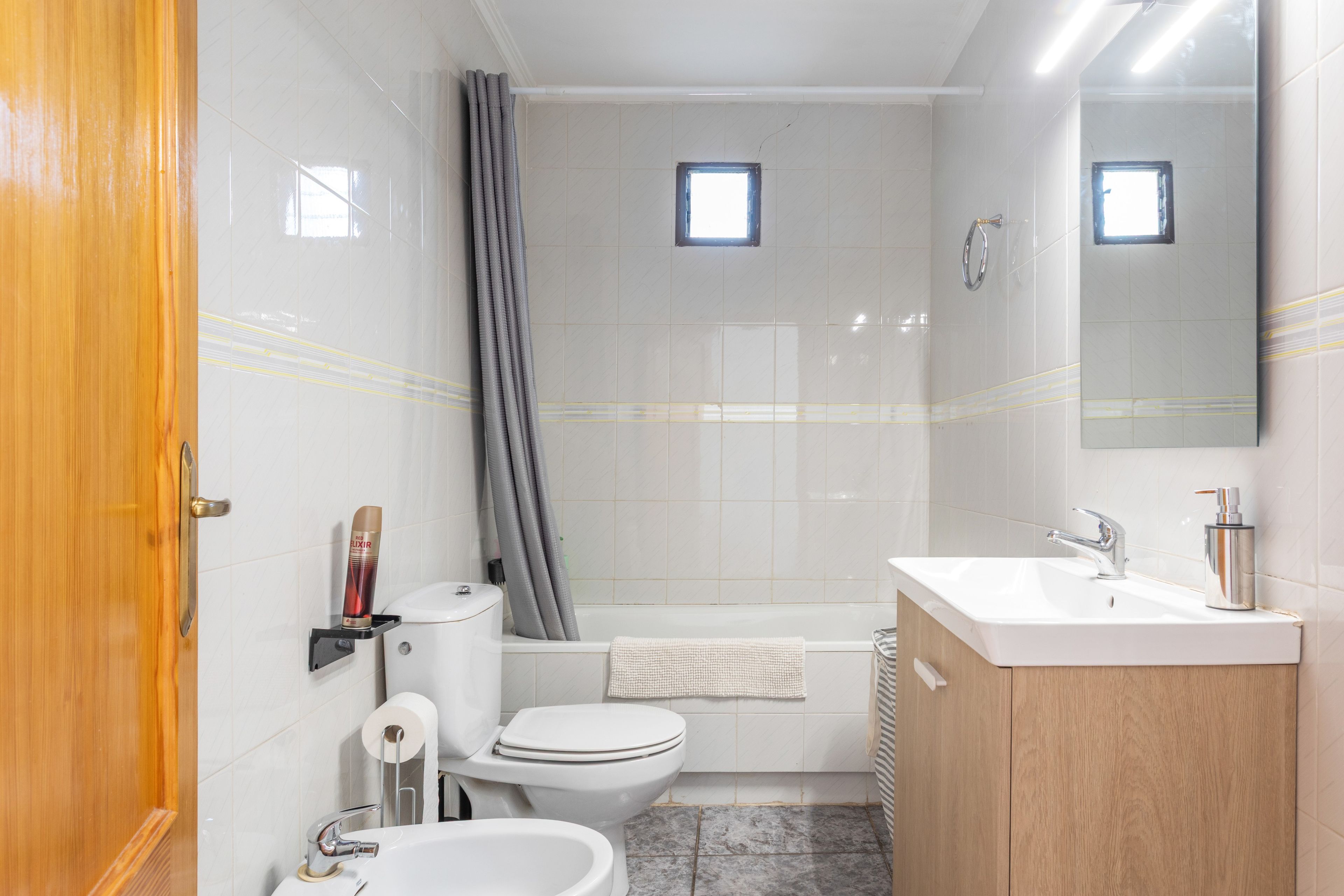 Un baño con inodoro, bidé, lavamanos y cortina de ducha.