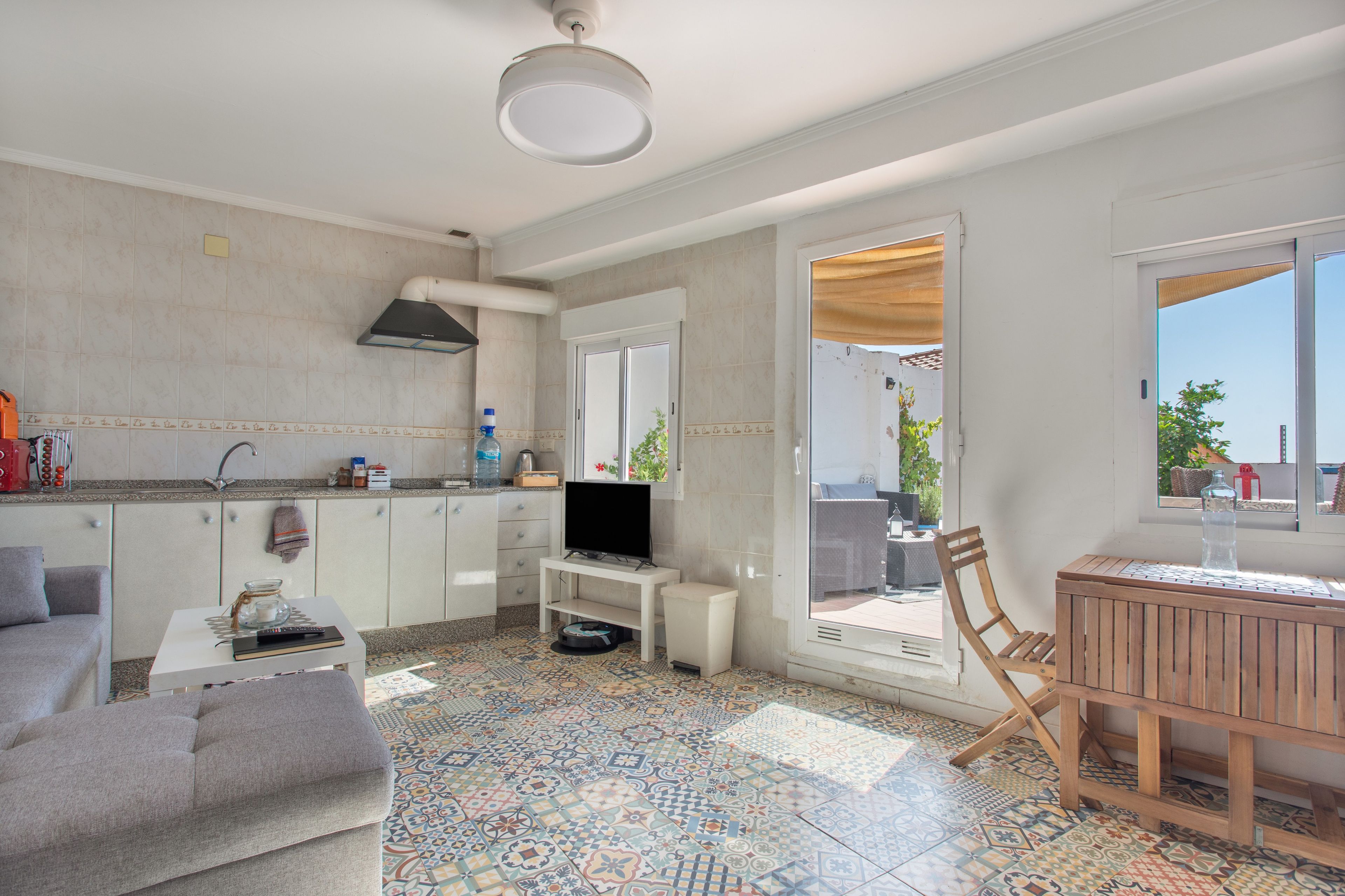 Una cocina moderna con armarios blancos, una campana extractora negra y un salpicadero de azulejos.