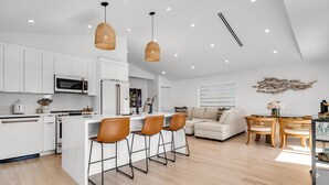A modern kitchen with white cabinets, a central island with bar stools, and pendant lighting.