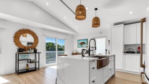 A modern kitchen with a large island, white cabinetry, and a hanging light fixture.