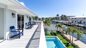 A balcony with outdoor seating, a pool, and a view of a marina.