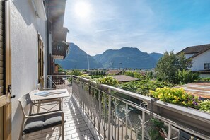 Ein Balkon mit Tisch und Stühlen, einer Brüstung und Blick auf Berge.