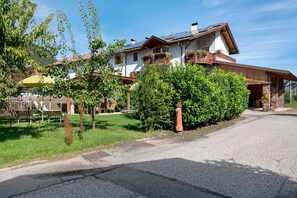 Une maison à deux étages, dotée d’un toit en pente, de panneaux solaires et d’un jardin bien entretenu.