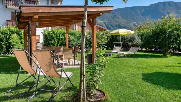 Une terrasse avec mobilier d’extérieur, une pergola et une vue sur les montagnes.
