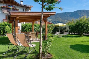Une terrasse avec mobilier d’extérieur, une pergola et une vue sur les montagnes.