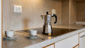 Un comptoir de cuisine avec une machine à café, deux tasses et une cuillère.