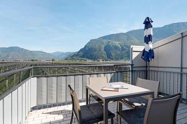 Un balcon avec une table et des chaises, donnant sur un paysage montagneux.