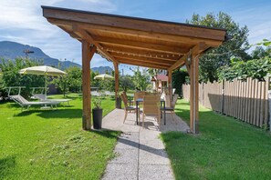 Une pergola en bois avec des sièges, un espace barbecue et une vue sur les montagnes.