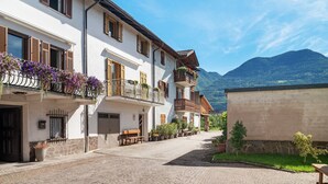 Un bâtiment européen traditionnel, doté de balcons, situé dans une rue pavée et offrant une vue sur la montagne.