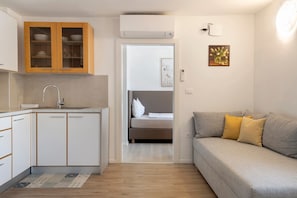Et lille værelse med tekøkken, seng og sofa.