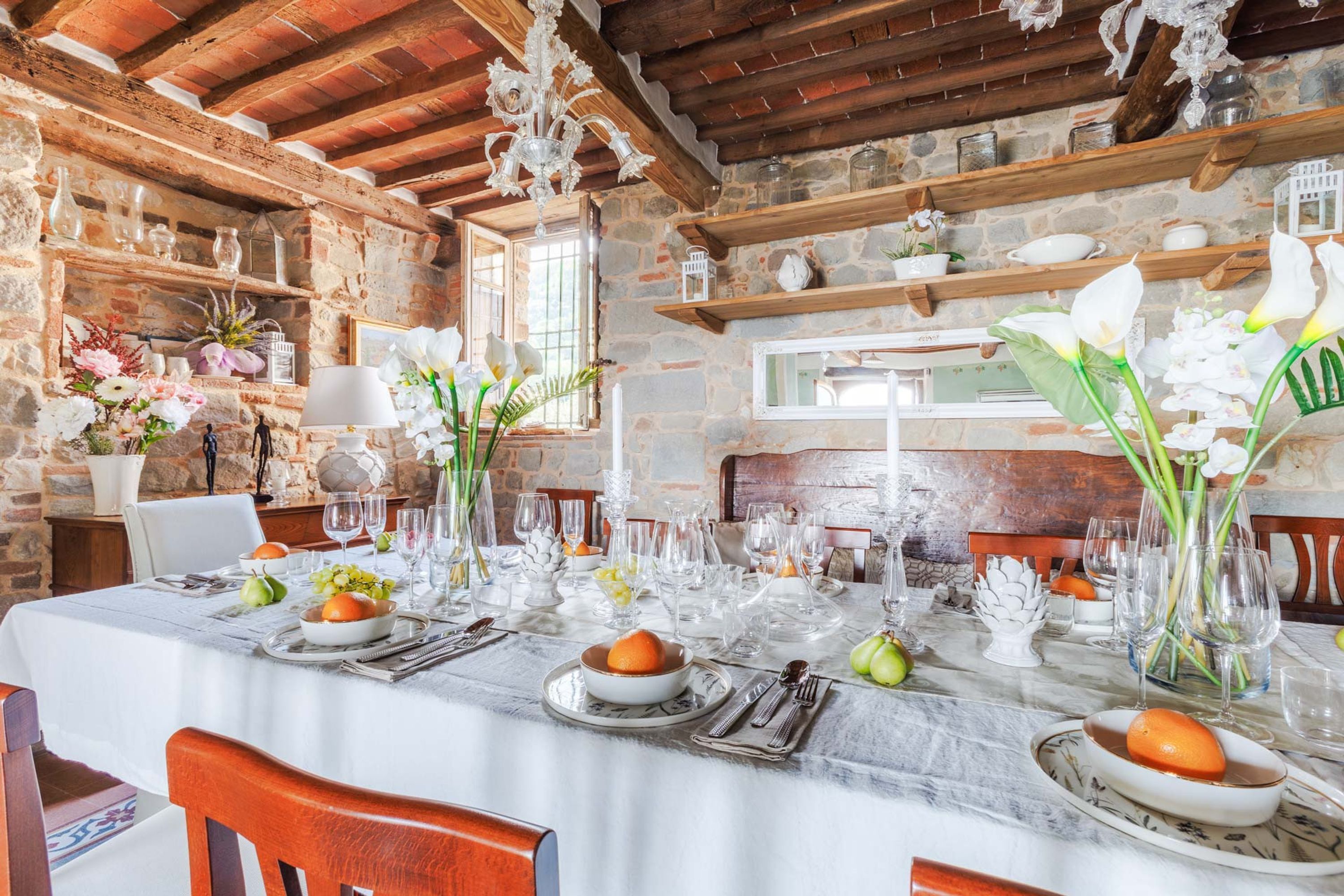 A dining area with a stone wall, wooden beams, and a table set for a meal.