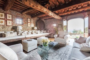 A rustic interior with stone walls, wooden beams, a sofa set, and a glass coffee table. - Villa Giannello Farmhouse (Capannori)