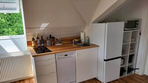 Et kompakt køkken med opvaskemaskine, mikroovn og indbygget ovn.