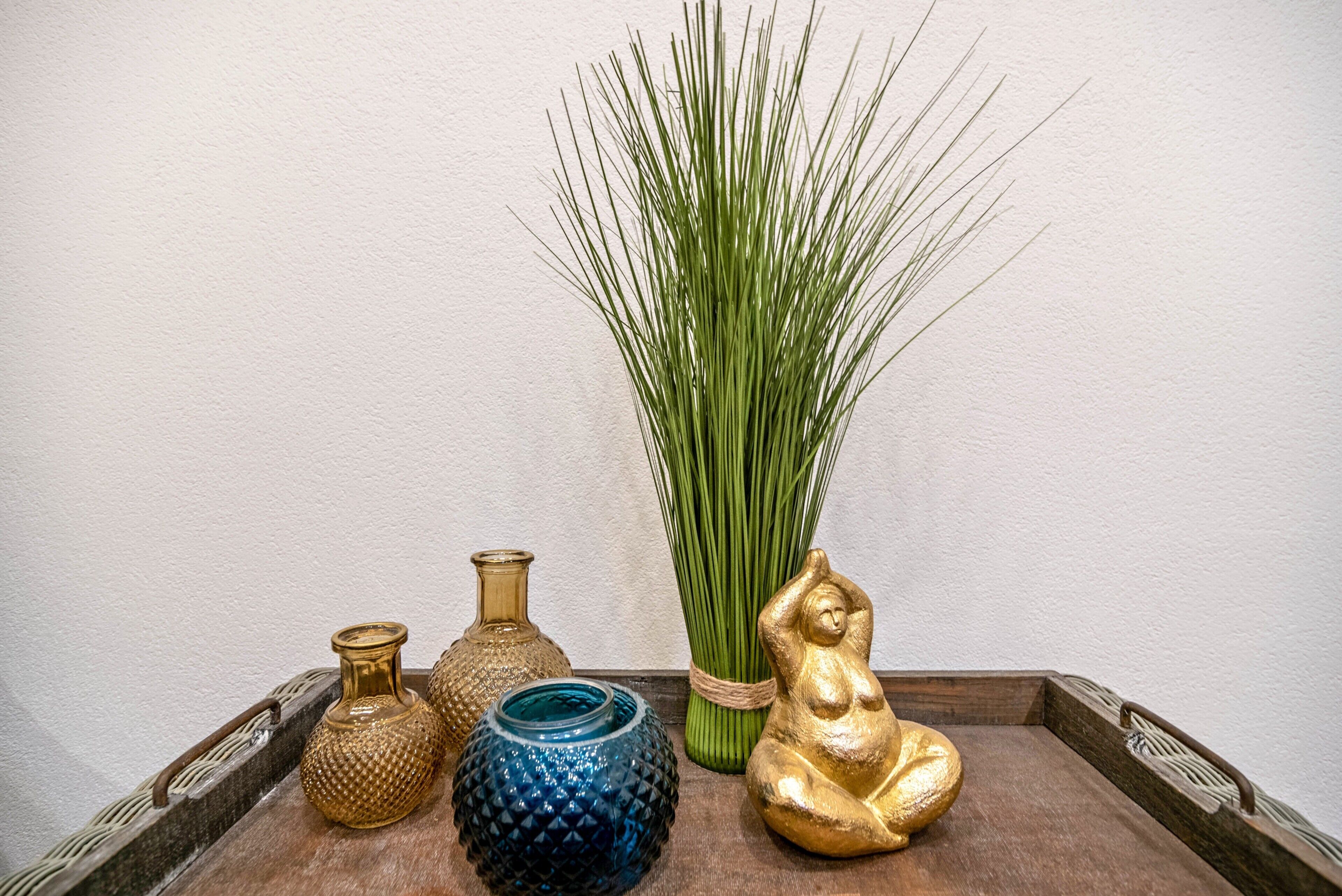 Een dienblad met decoratieve vazen en een hoge groene plant.