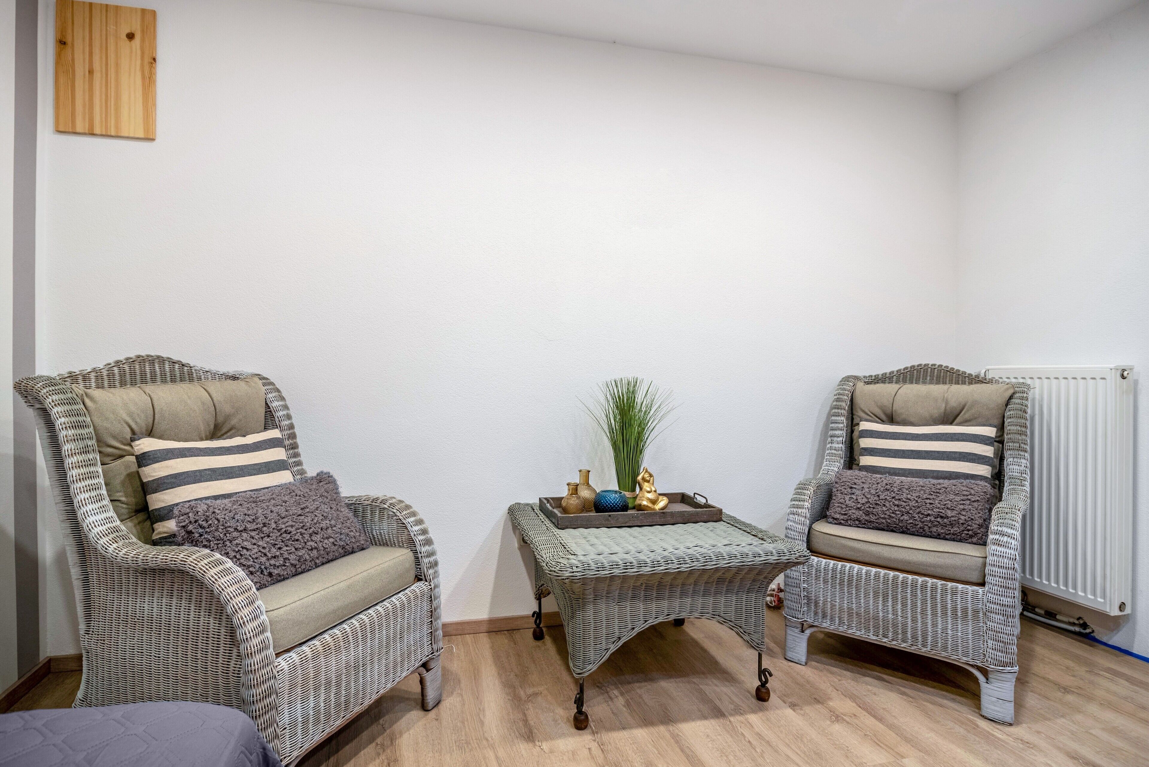 Two wicker armchairs with cushions, a small table with decorative items, and a radiator.