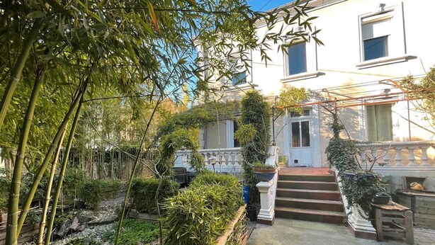 A garden with bamboo, a white building with a staircase, and a small wooden bench. - Bed and Breakfast 'Chambre Spacieuse' with Shared Terrace, Shared Garden and Wi-Fi (Le Teil)