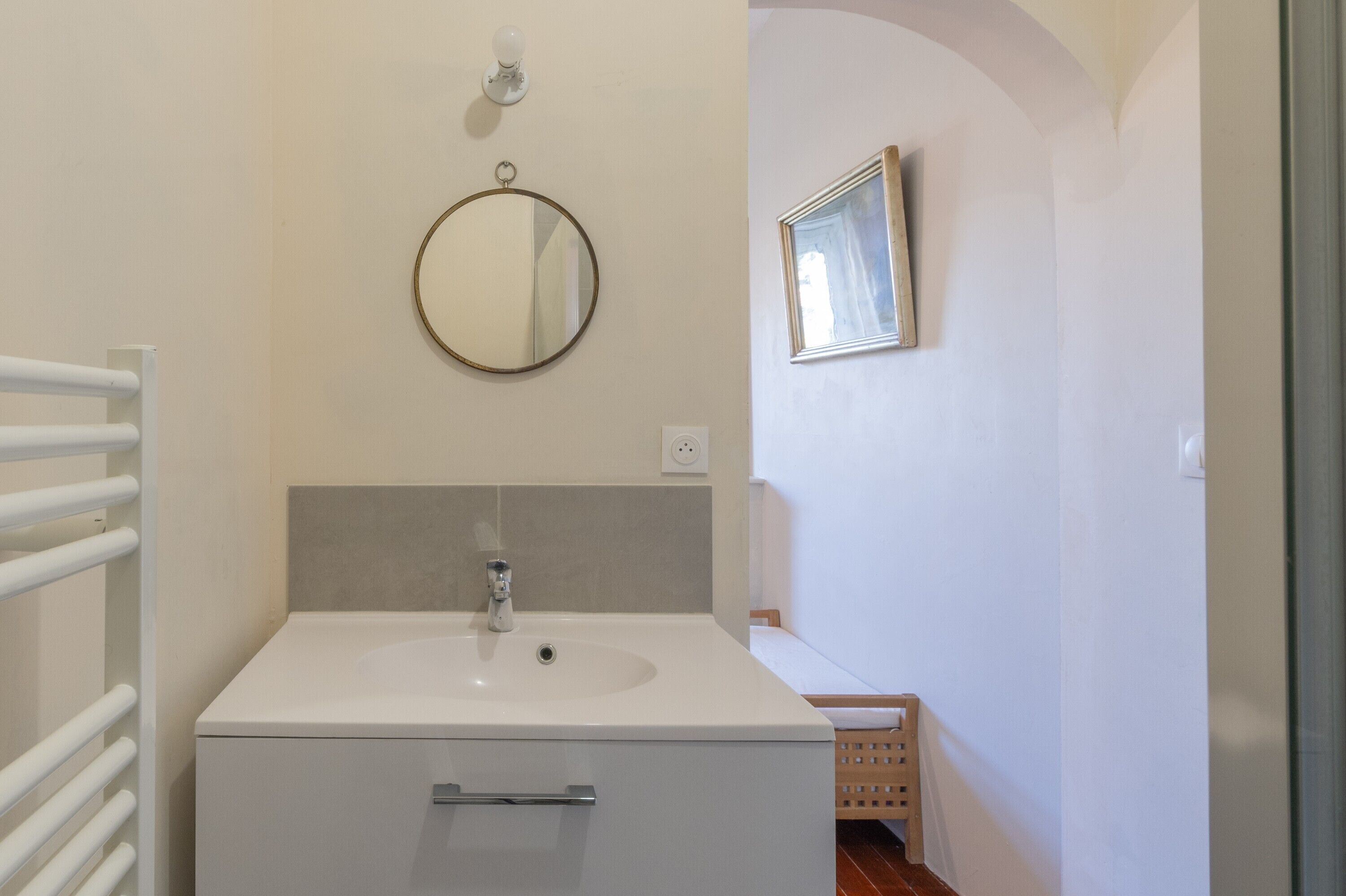 A bathroom with a white sink, a mirror, and a wooden cabinet.