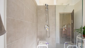 A shower area with a glass door, a white towel rack, and a small step stool. - Apartment 'Bleue' with Shared Terrace, Shared Garden and Wi-Fi (Le Teil)