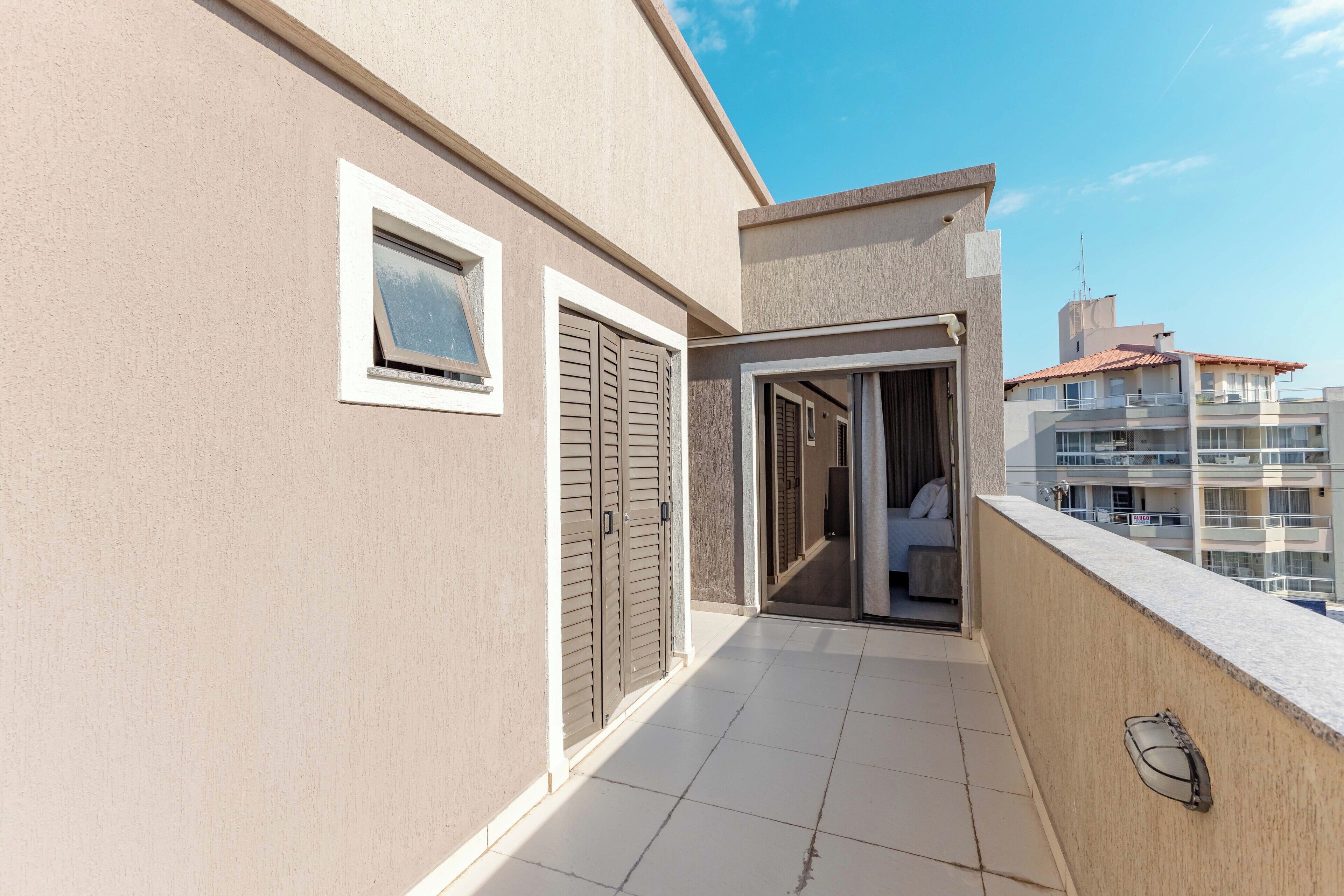 A modern apartment with a balcony, a sliding door, and a view of neighboring buildings.
