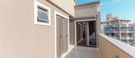 A modern apartment with a balcony, a sliding door, and a view of neighboring buildings.