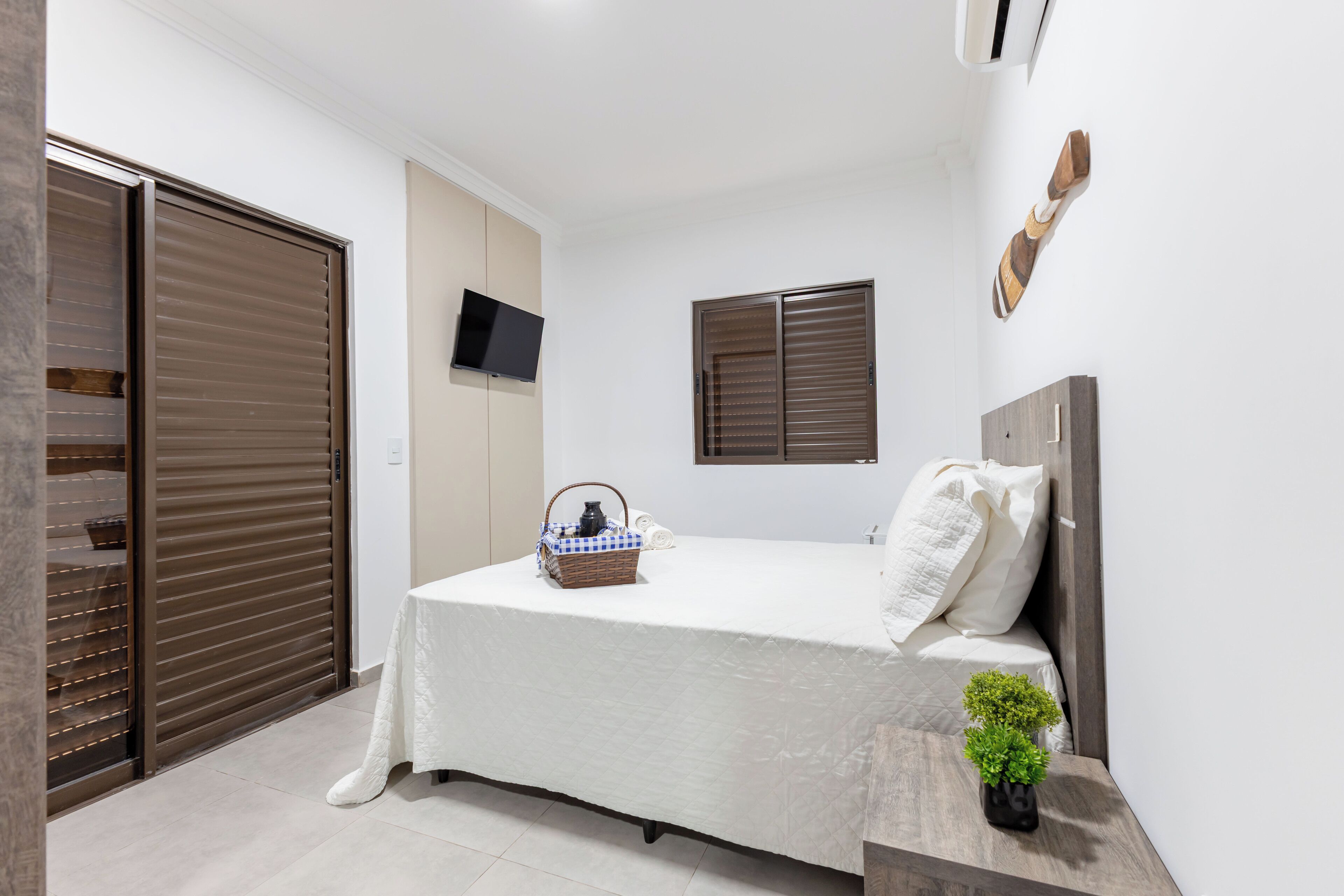 Une chambre à coucher avec un lit, une télévision, une fenêtre et une armoire.