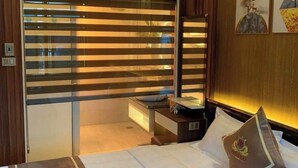 Una habitación de hotel con cama, mesita de noche, aire acondicionado y ventana con persianas.