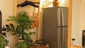 Una cocina compacta con un refrigerador, estantes de madera y plantas en macetas.