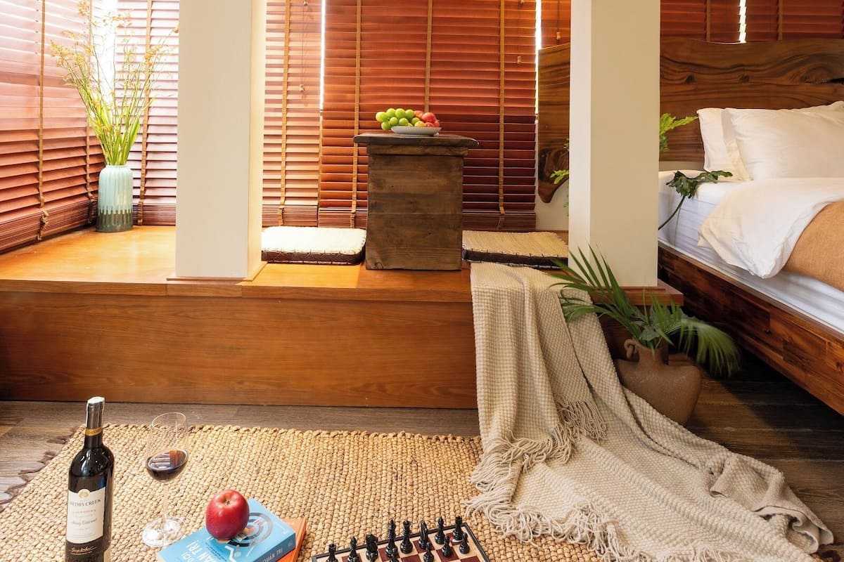 Una habitación con una cama, un tablero de ajedrez, un libro, una botella y una planta.