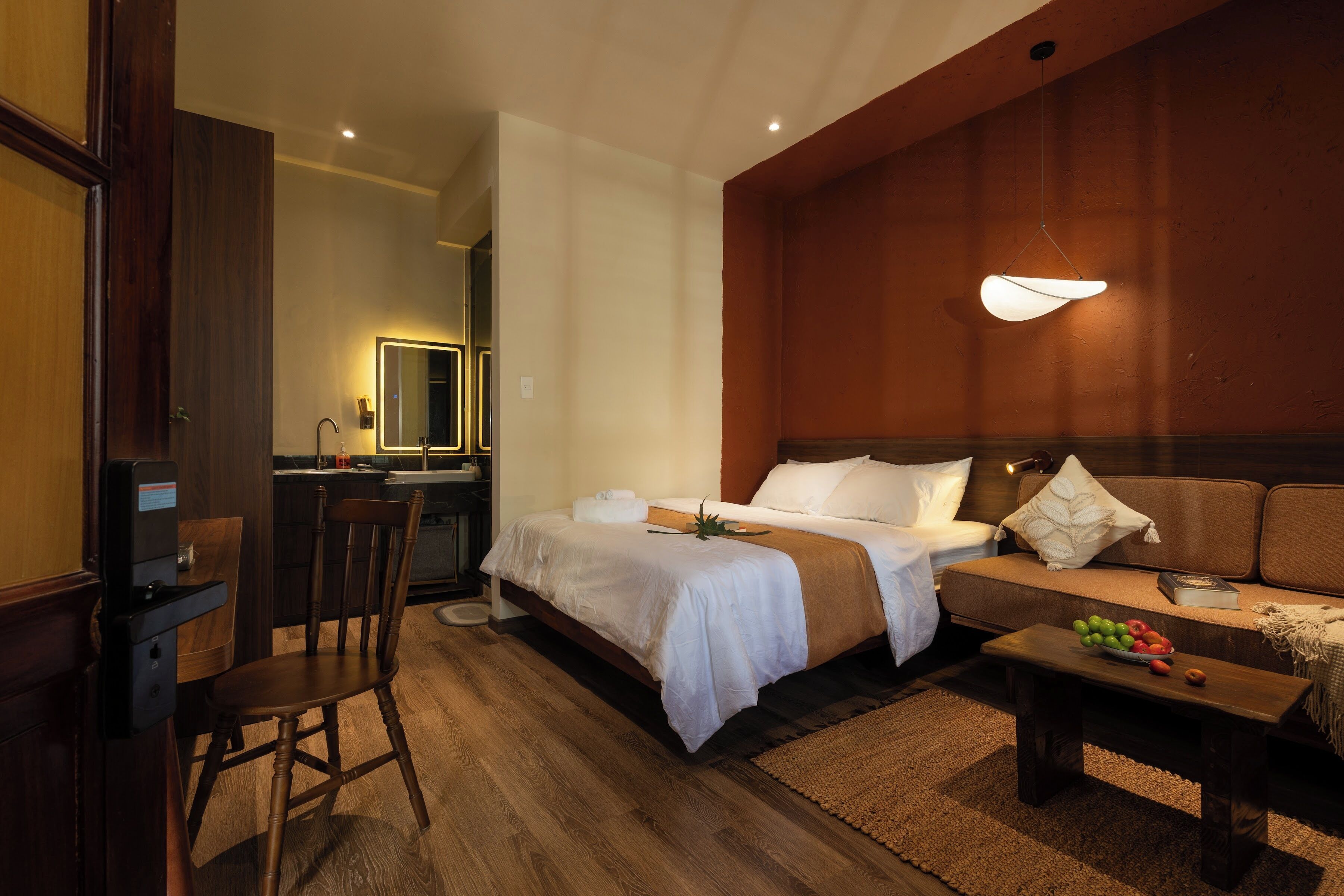 A hotel room with a bed, a sofa, a desk, and a chair.