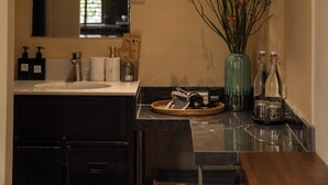 Un baño con espejo, lavamanos y un florero.